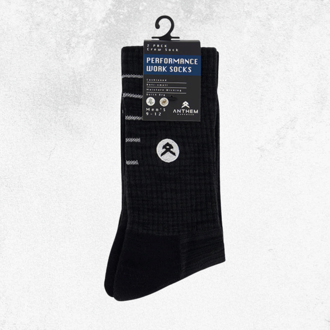A pair of black performance work socks hanging from a black plastic hanger with a product label. The socks feature a subtle grid pattern and a white circular logo on the lower leg.