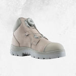 A light beige safety boot with a grey sole and a grey dial closure system on the side, shown against a textured light grey background.