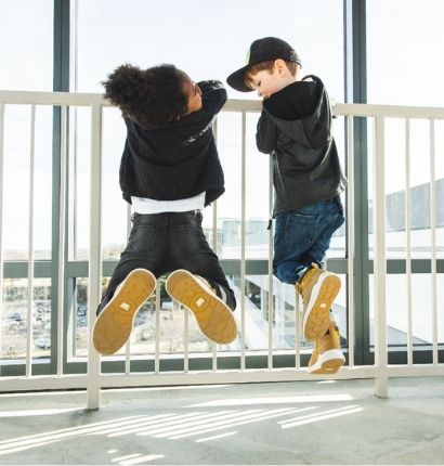 Two Kids hanging from gate rail. 