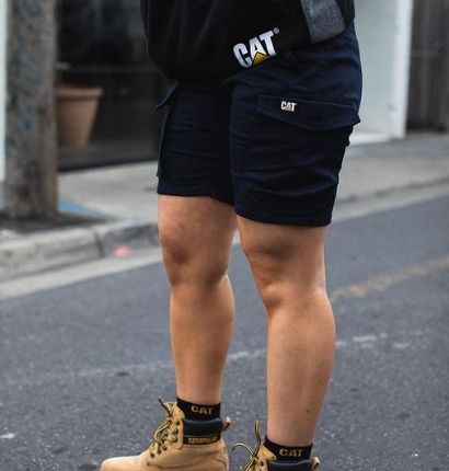 Woman Standing outside on concrete wearing CAT Diesel Short. 