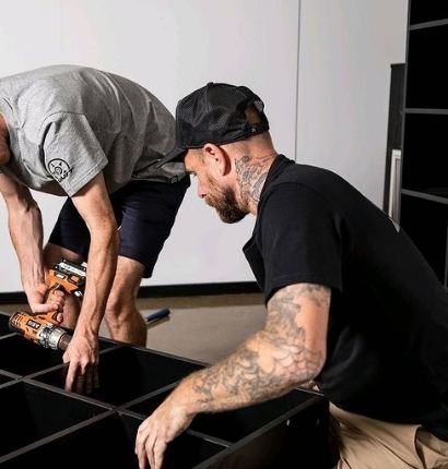 Two Men building a shelf wearing the UNIT Elite Trucker Cap 