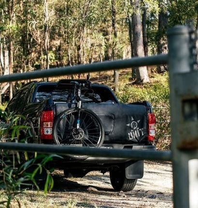 Ute with mountain bike hanging out of the back in the Australia bush. 
