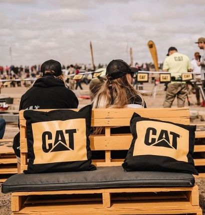 Couple sitting on pallet seat with Cat pillows around them. 