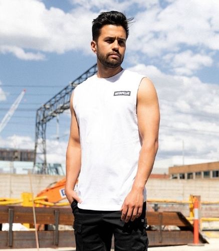 Man Standing on construction site wearing the CAT Icon Muscle Tank Tee. 