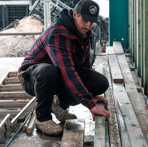A man wearing the JetPilot Quilted Men's Flannel Jacket and working
