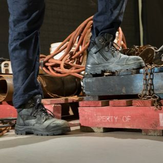 A boot angled toward camera with hazard banner Background