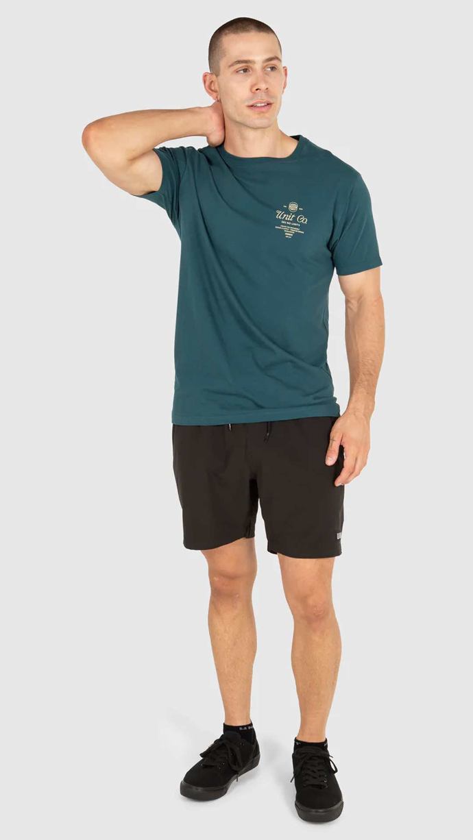 Man wearing dark teal UNIT Men's Tee - Rival in studio