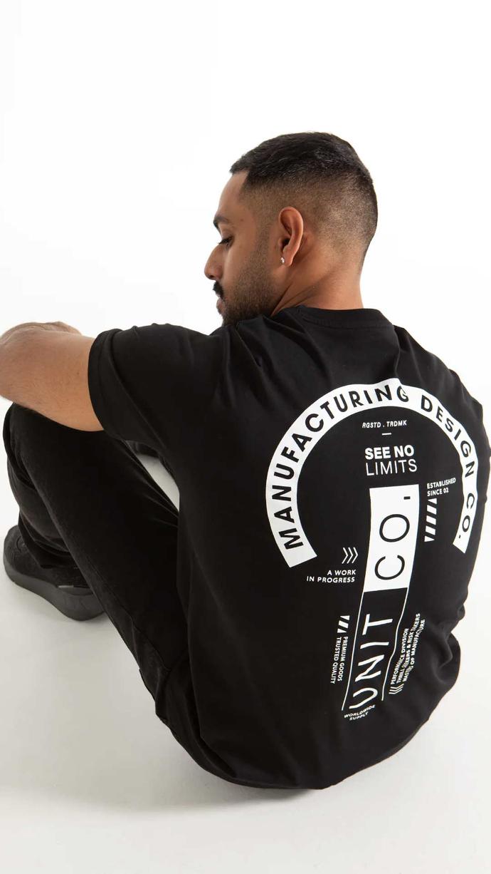 Man on the ground wearing black UNIT Men's Tee - Validate in studio