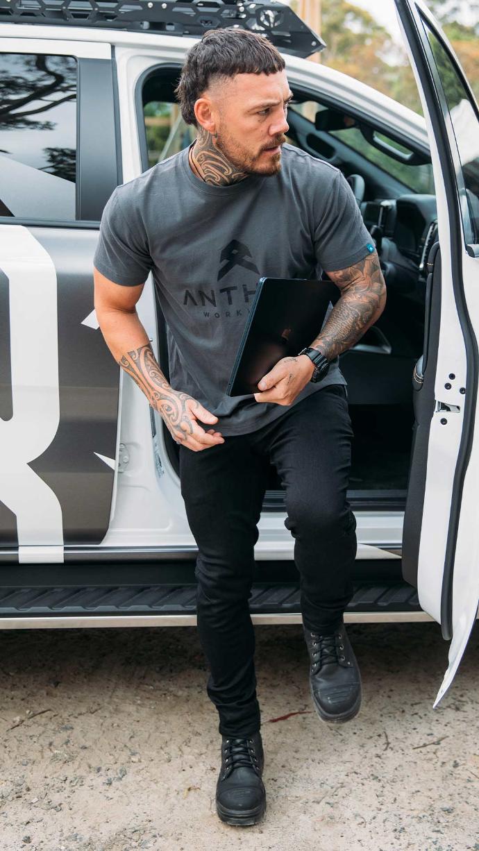 Tradie with tattoos wearing Black Anthem Tech Stretch Denim Jeans and stepping out of car.